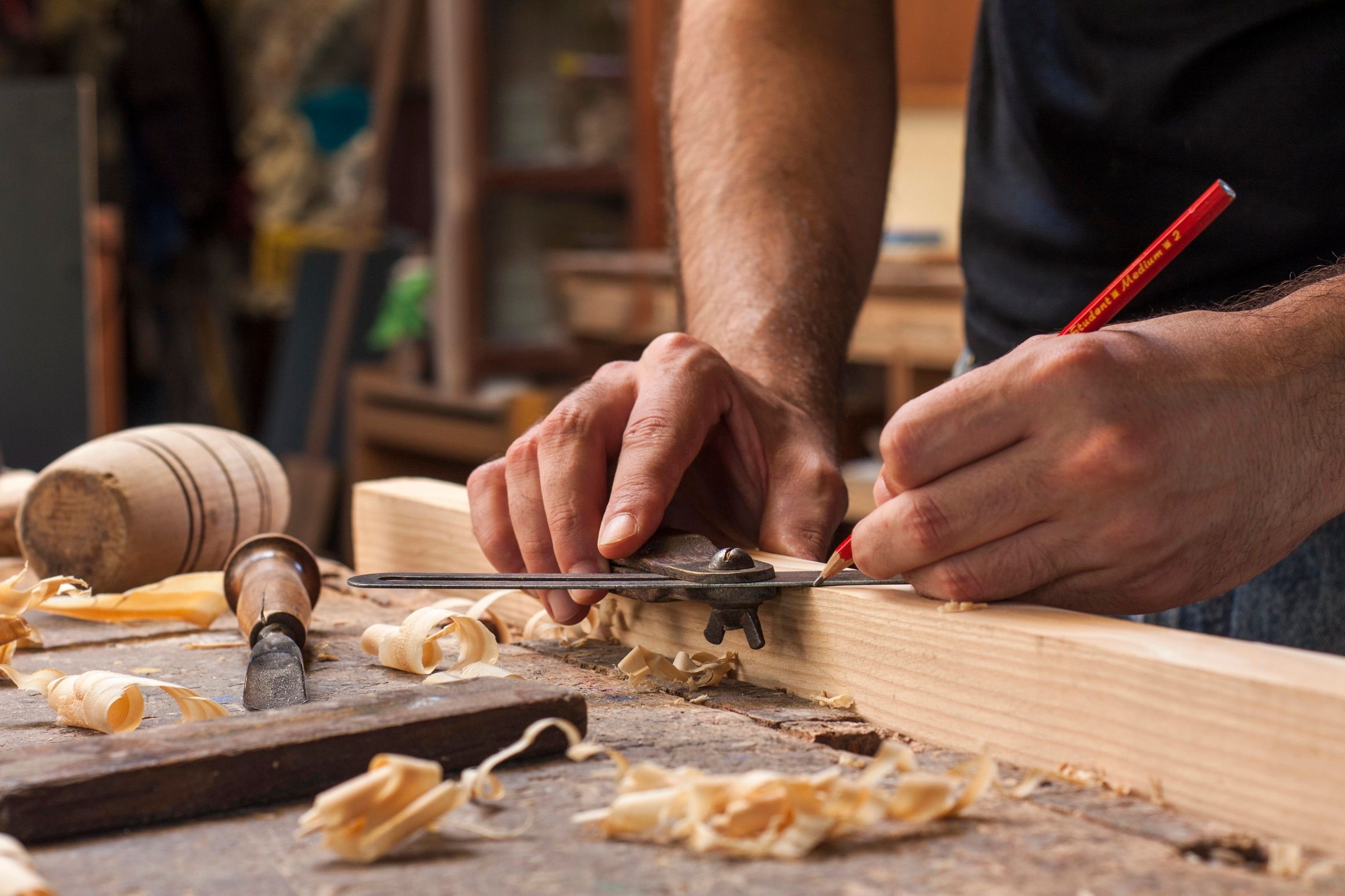 Tâmplar care trasează pe o scândură în atelier